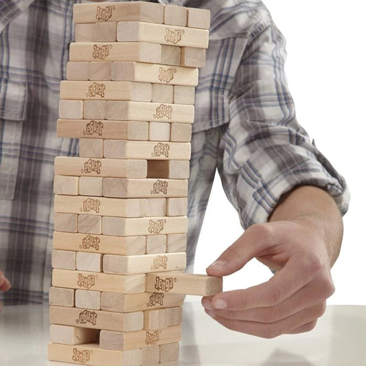 Person playing with a wooden block tower game, likely Jenga, on a white background.