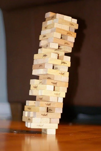 Stack of wooden blocks with names on them, leaning against a dark background