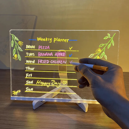 Clear LED board with a weekly planner and a hand holding a pen.